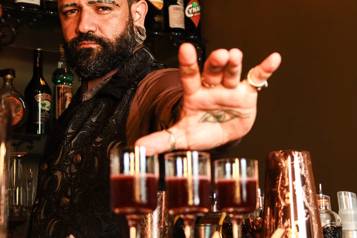 Bartender diante da fileira de drinks preparados